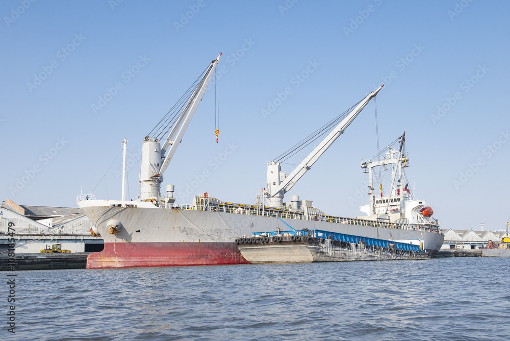 Container Cargo freight ship with working crane bridge in shipya