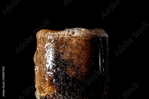 Soda large glass, overflowing glass of soda closeup with bubbles isolated on black background
