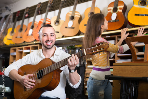 Couple playing guitars in music shop.