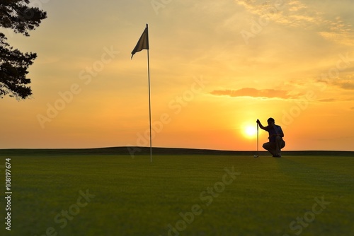 Young man playing golf at sunset