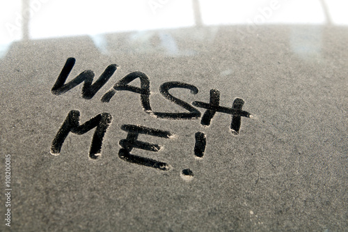 Car dust word on dirty rear window of the car and inscription WASH ME!. Front and side view of mirror. Close up of text with handwriting.