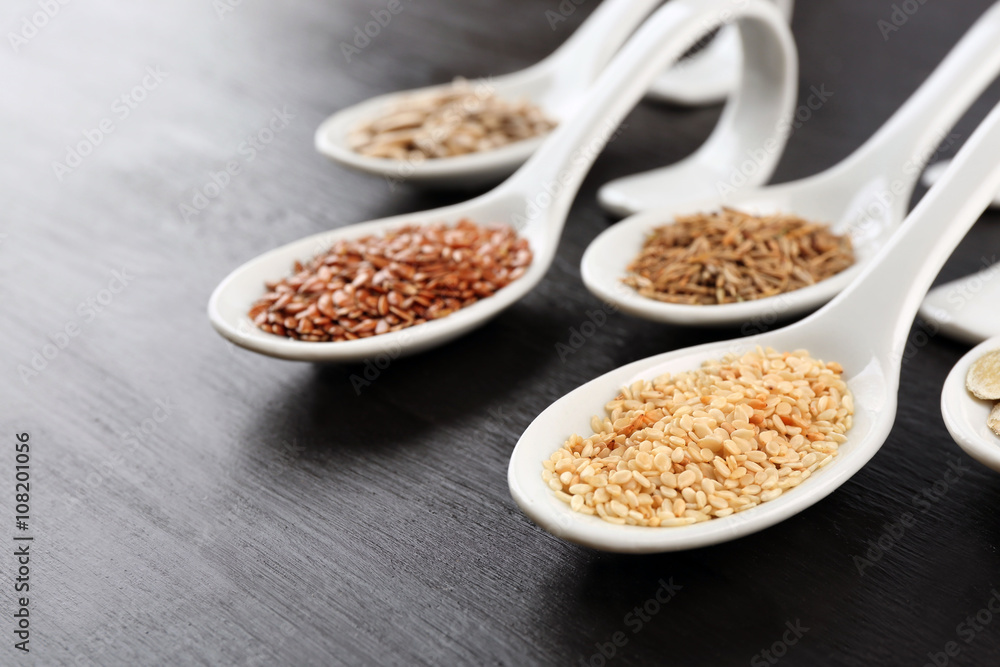 Different kinds of seeds in spoons on wooden table Different kinds of seeds in spoons on wooden table