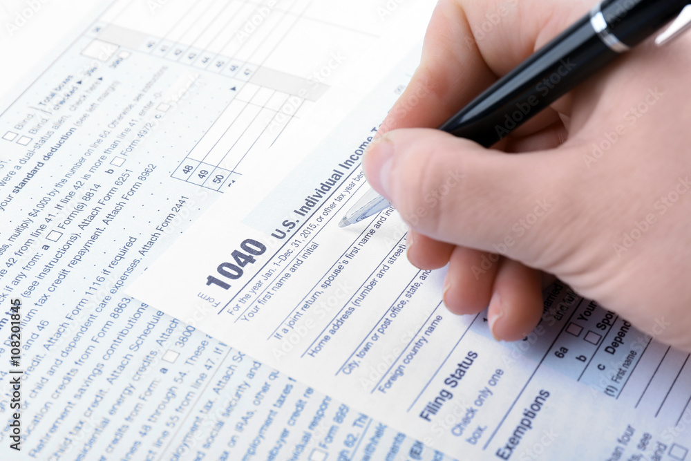 Female hand filling in the Income Tax Form, close up Female hand filling in the Income Tax Form, close up