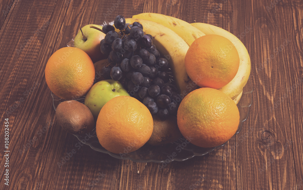 Oranges, apples, bananas and grapes are in dish Oranges, apples, bananas and grapes are in dish