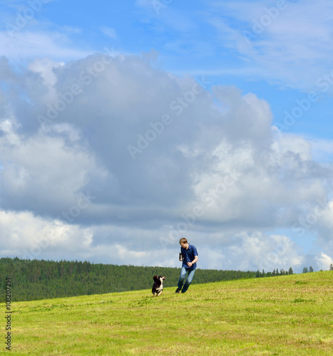 Summer landscape. Sky, clouds, space, running young man and dog