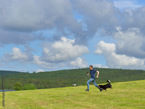 Summer landscape. Running young man and dog