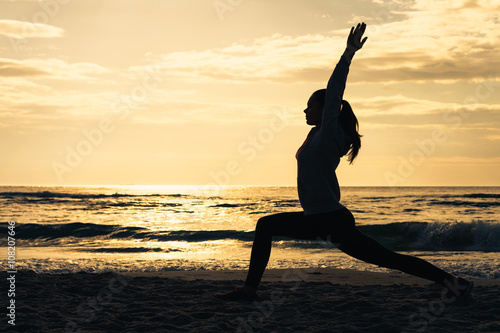 Silhouette of a woman on the beach during morning exercises at s
