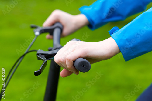 A close up view of a stylish girl riding a bicycle in the green park in summer. Wearing blue stylish clothes. © dapunk