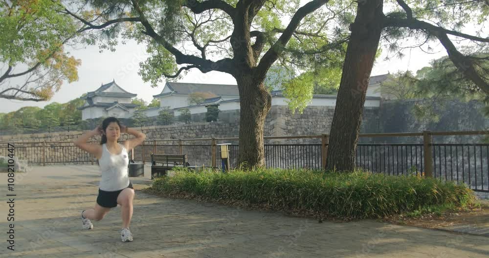 Young Japanese women doing stretches lunges in park Osaka castle background Young Japanese women doing stretches lunges in park Osaka castle background