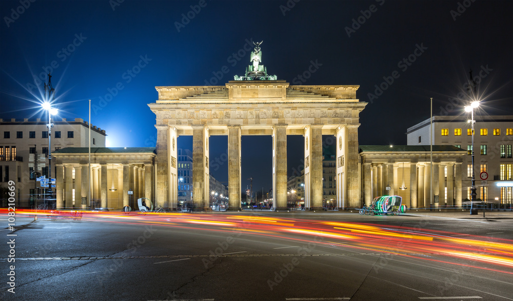 Fototapeta premium Brandenburger Tor in Berlin bei Nacht mit roten Verkehrslichtern