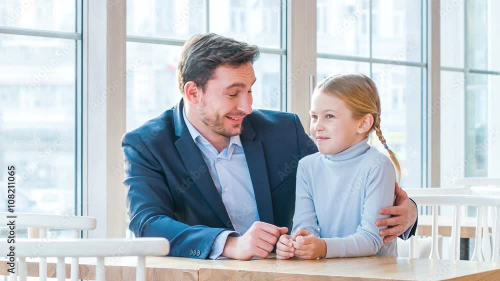 Positive father and his little daughter sitting in the cafe Positive father and his little daughter sitting in the cafe