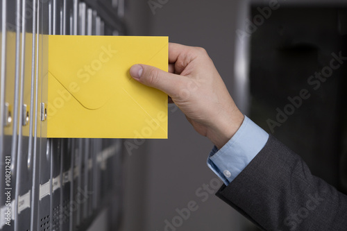 Close up of hand putting the yellow letter into the mailbox   photo