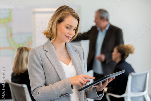 Casual businesswoman using her tablet during a meeting in the office
