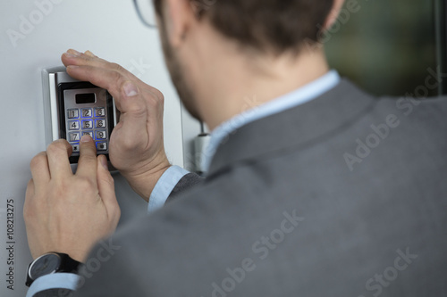 Close up of businessman hand entering pressing button on security system