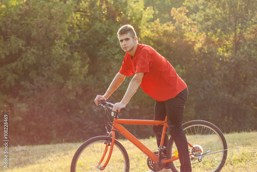 Man ride orange bike at meadow