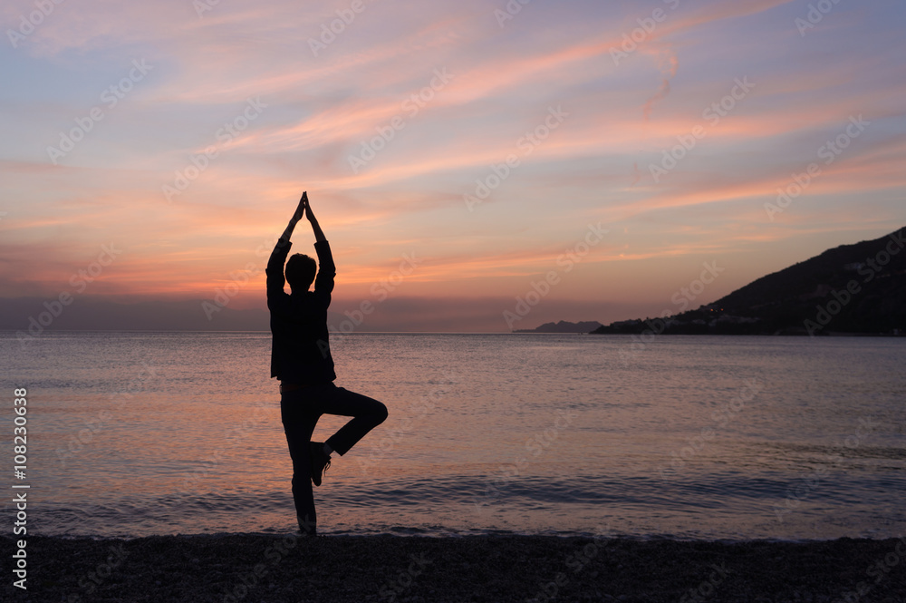 Yoga silhouette on the beach at sunset