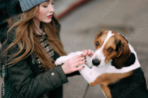 Young hipster girl with her pet estonian hound dog playing, junping and hugging and having fun outdoor at the old stadium. © dashamuller