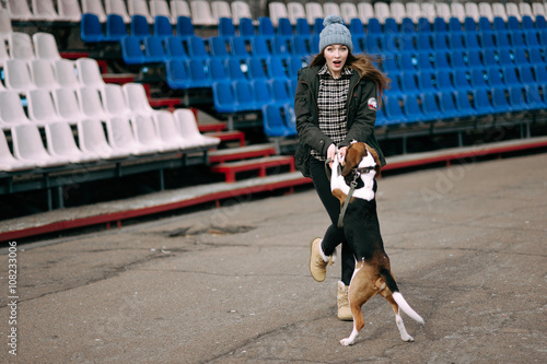 Young hipster girl with her pet estonian hound dog playing  junping and hugging and having fun outdoor at the old stadium.