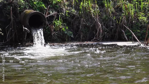 Water running out of storm water pipe into a lake.