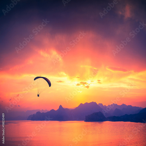 Paraglide silhouette over the sea sunset