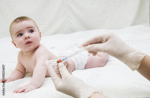 Infant child baby kid creep and hand with medical insulin syringe ready for injection 