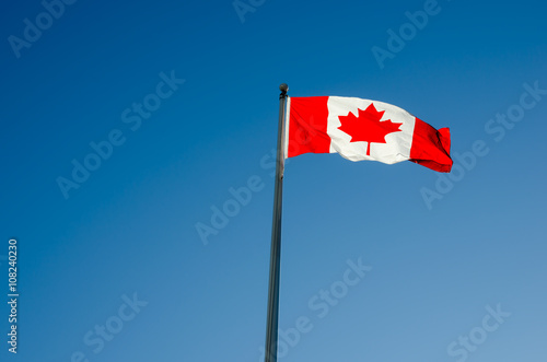 Canadian flag waving over blue sky