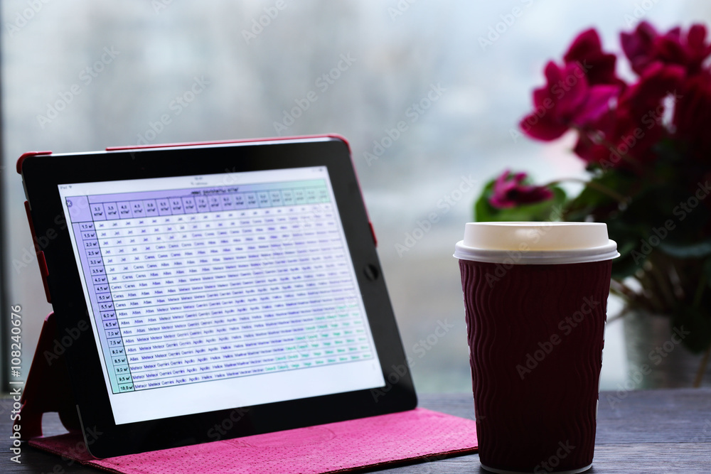 Tablet with tables , cup of coffee  by the window