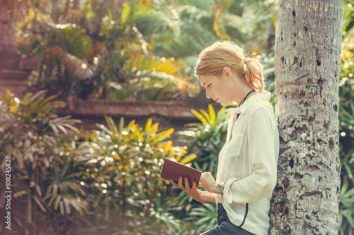 A portrait of a young woman reading a book in the park © triocean