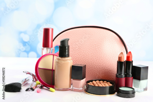 Makeup set with beautician, eyelash curler, brushes and cosmetics on light background
