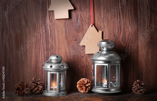 Silver lanterns with pine cones on wooden background