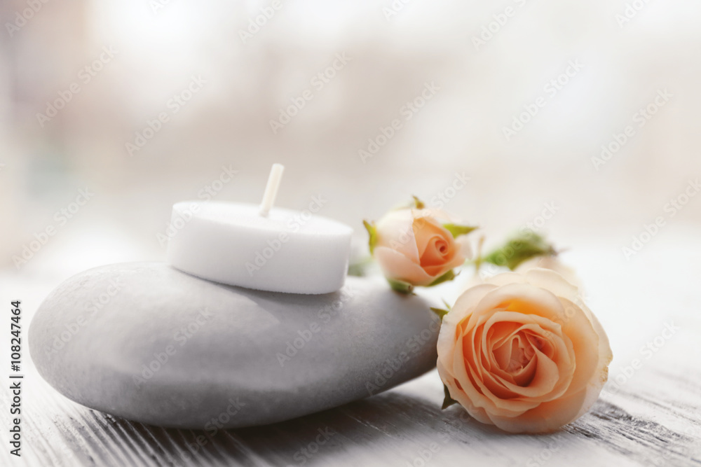 Spa stones with beautiful flowers and candle on white wooden table