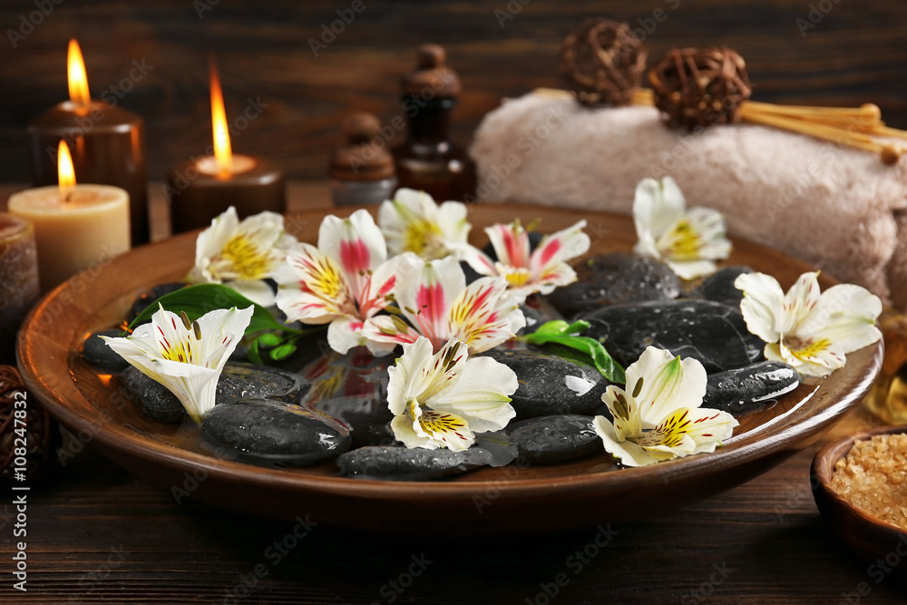 Spa wooden bowl with water, flowers and stones closeup Spa wooden bowl with water, flowers and stones closeup