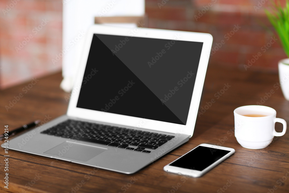 Workplace with laptop, mobile phone and cup of coffee indoors Workplace with laptop, mobile phone and cup of coffee indoors