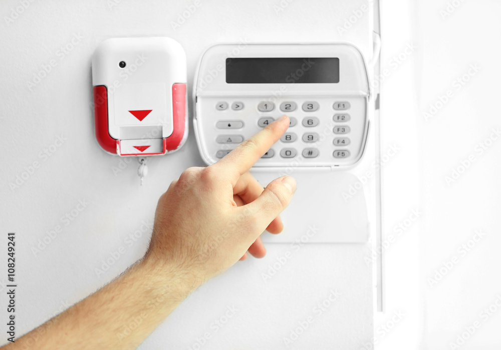 Male hand entering code on security system keypad indoors Male hand entering code on security system keypad indoors
