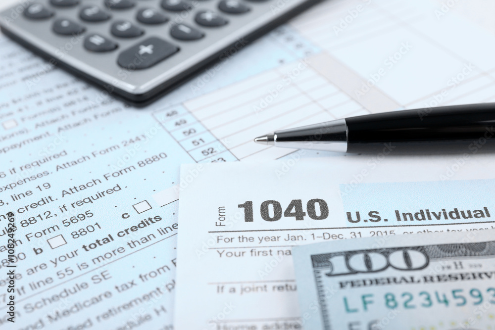 1040 Income Tax Form and dollar bills, close up 1040 Income Tax Form and dollar bills, close up