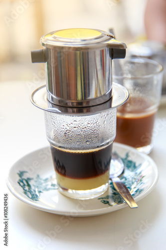 Traditional Penang kopitiam (or kopi tiam) style milk coffee in vintage mug, fractal on the cup is generic print. Close-up view with dramatic, ambient light on wooden background photo