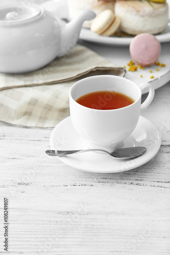 Cup of tea with macaroons on wooden background