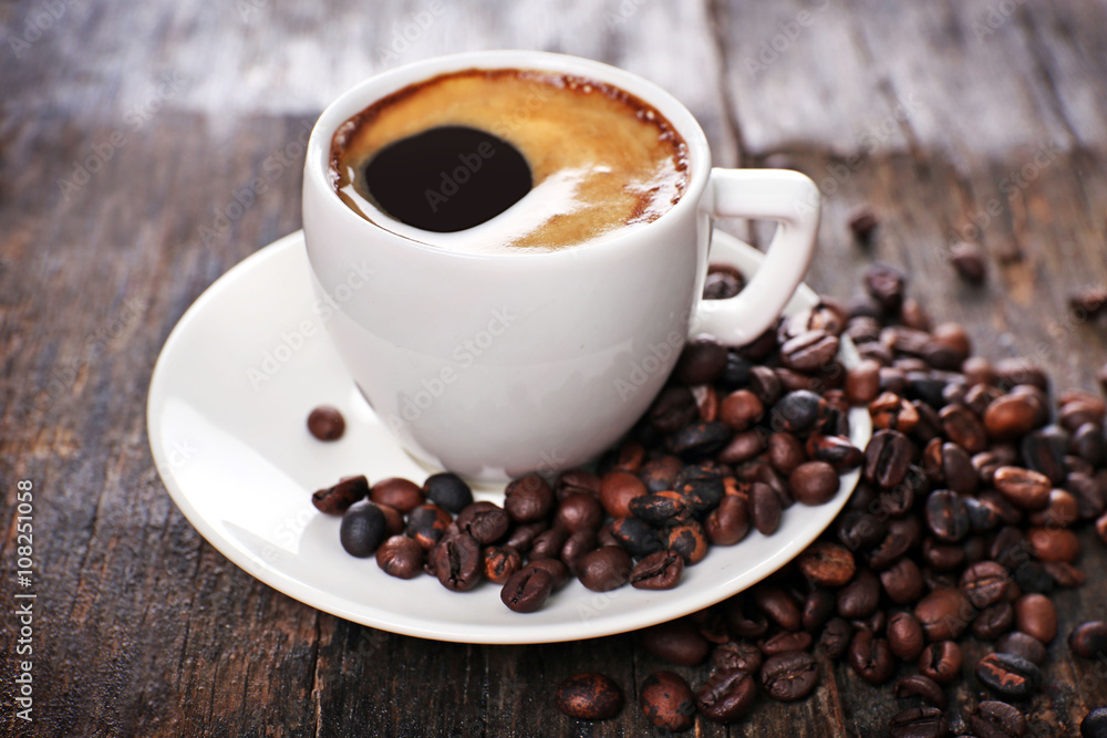 Obraz premium Cup of hot coffee with roasted beans on rustic wooden background