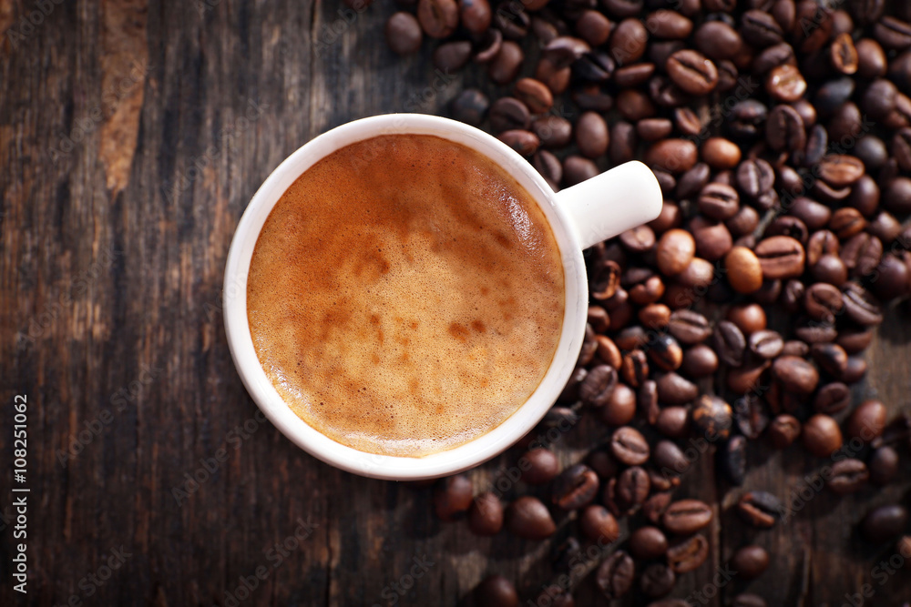 Cup of hot coffee with roasted beans on rustic wooden background Cup of hot coffee with roasted beans on rustic wooden background