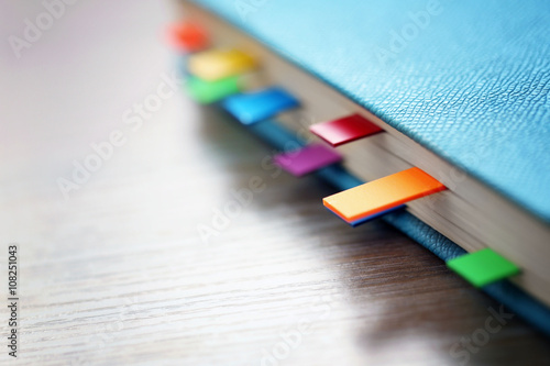 Billede på lærred Blue dairy with multicoloured stickers on wooden background, closeup