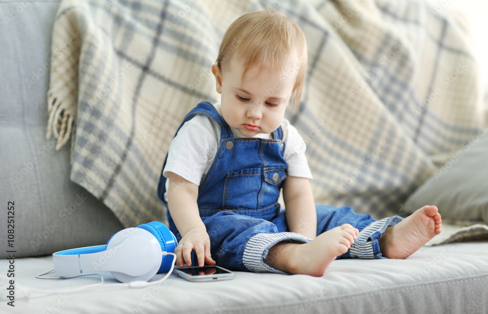 Baby with headphones sitting on sofa Baby with headphones sitting on sofa
