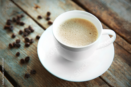 Cup of fresh coffee with beans on wooden background