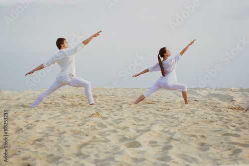  beautiful, athletic couple in white clothes making yoga exercis