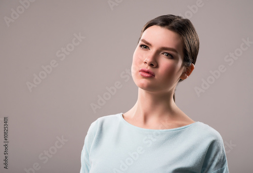 Serious girl standing isolated on grey background    