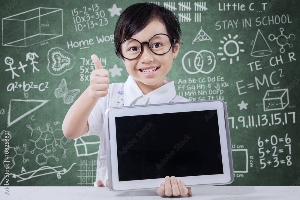 Cute girl shows tablet and thumb up in class