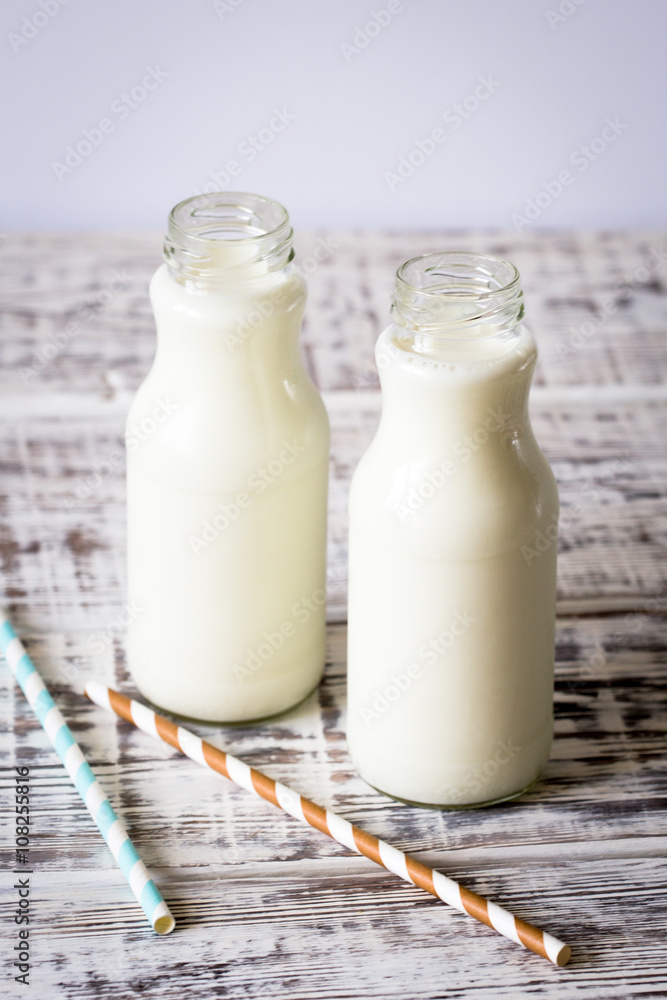 Two bottles of milk with striped straws standing on old table. Two bottles of milk with striped straws standing on old table.