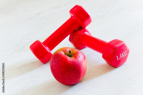 Fitness dumbbells and red apple