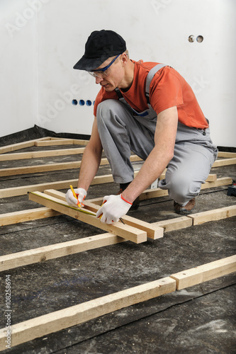 Worker measures off a wooden beam.