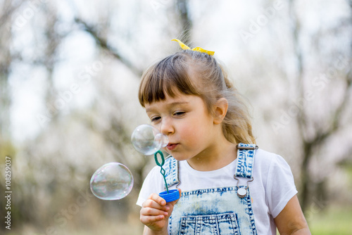 little girl inflates soap bubbles