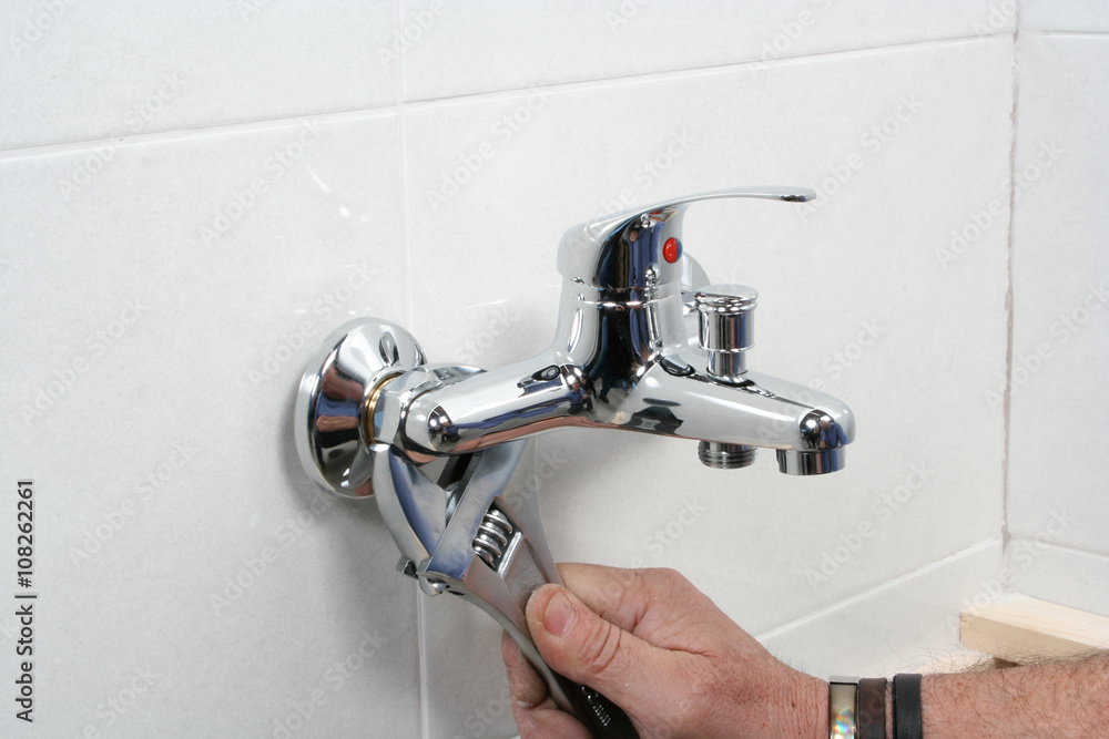 Plumber repairing a faucet in a bathroom Plumber repairing a faucet in a bathroom